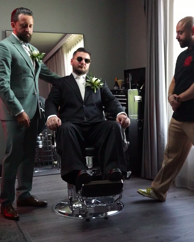 Bräutigam im Barberstuhl mit Trauzeugen am Hochzeitsmorgen